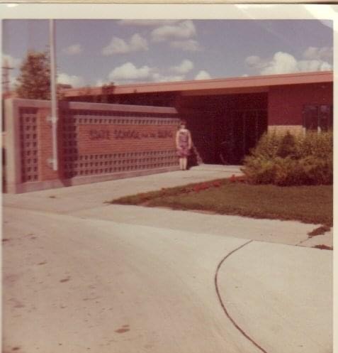 A young Carmen stands in front of the main entrance at the School for the Blind in Grand Forks circa 1070.