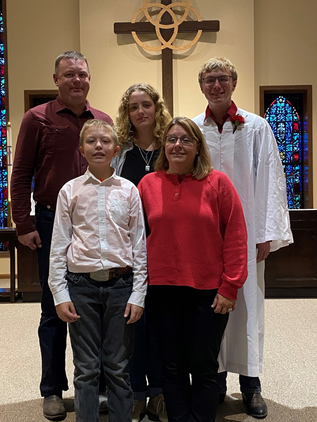 A picture of Erin with her husband and three children in church together with a wood cross behind them.