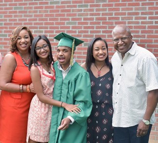 The Morris family at Malik's graduation. Malik stands in the center in a green cap and gown.