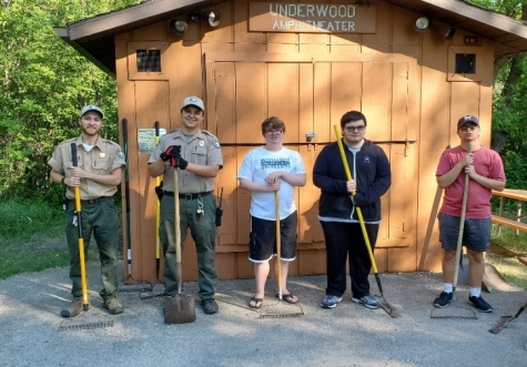 3 high schoolers and two park rangers hold brooms at Turtle River State Park.