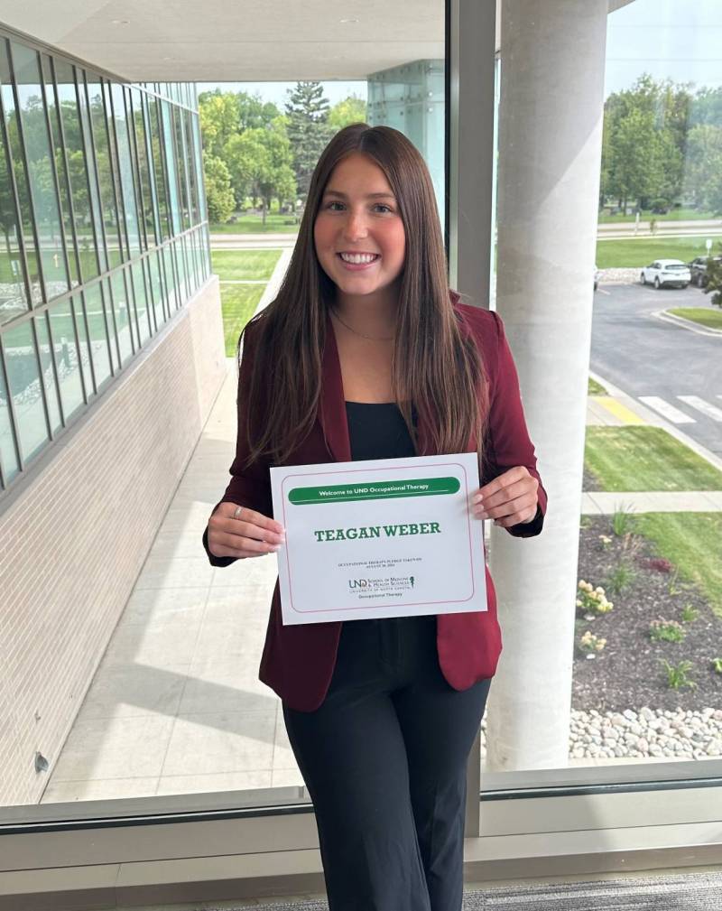 Teagan proudly holds a certificate of acceptance into the OT Program at UND.