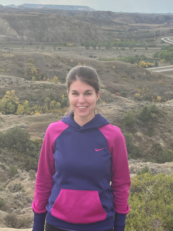 Candace stands smiling in Medora while hiking.