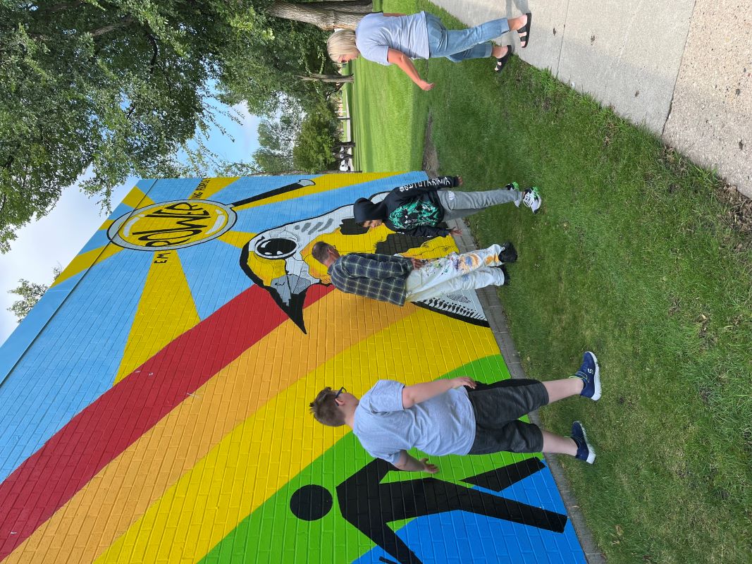 Students and the artist interacting with the mural, touching it and looking at it up close.