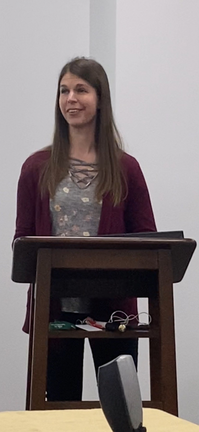 Candace stands behind a podium speaking.