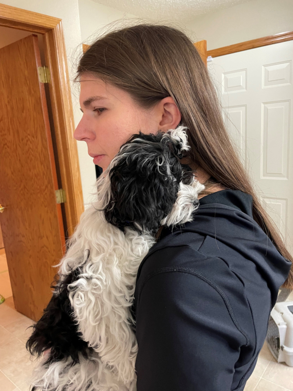a profile of Candace holding her dog, Cooper, who is black and white.