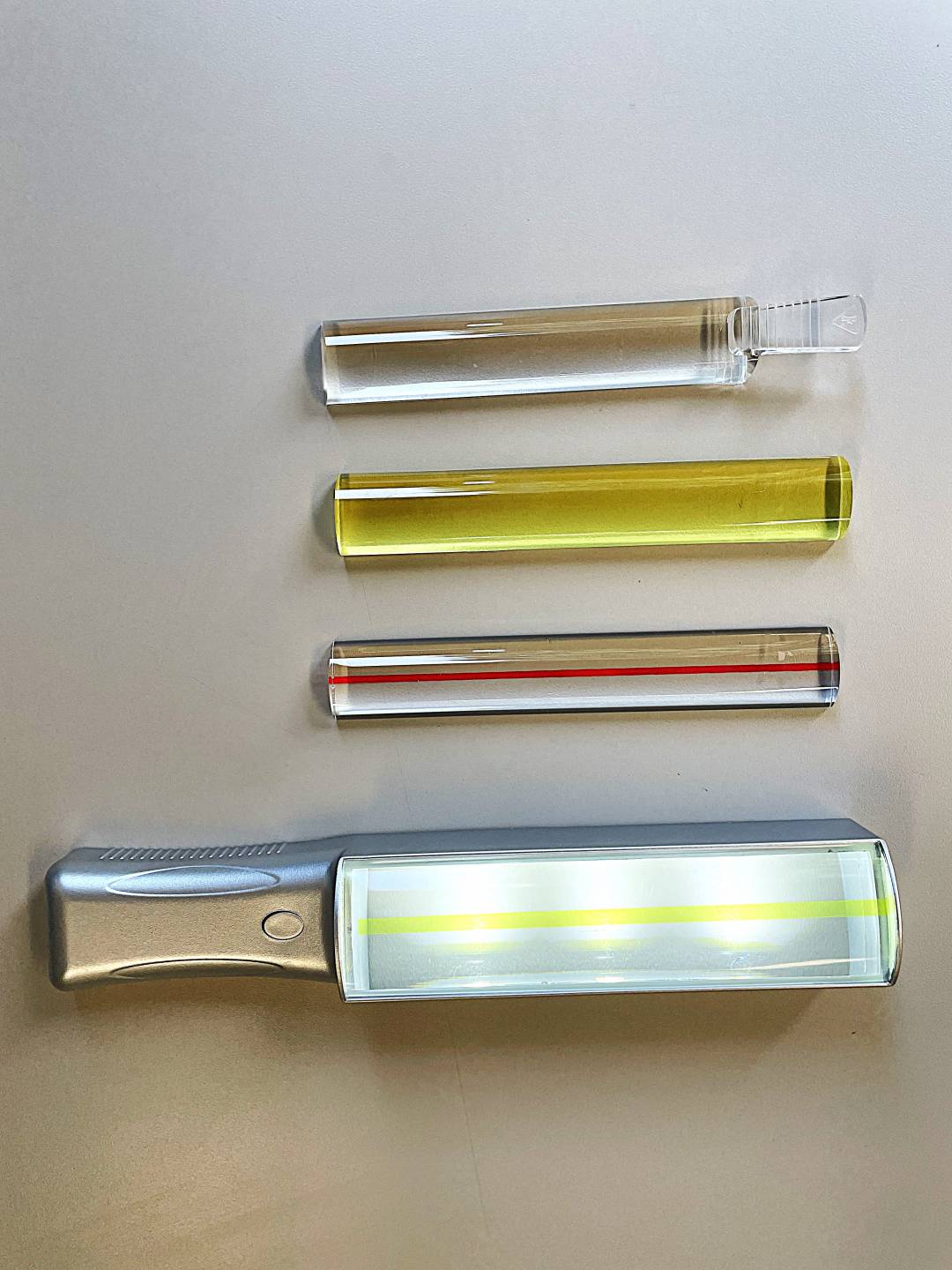 Clear 6 inche bar magnifier with finger grip on end, yellow 6 inch bar magnifier, clear 6 inch bar magnifier with red line down center, illuminated 6 inch magnifier with large handle