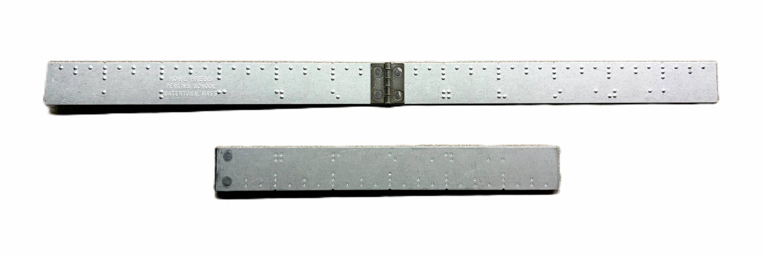 1 foot long aluminum ruler with hinge in the center. 3 dots and the number in braille at every inch, two dots at every half inch, and 1 dot at every quarter inch.