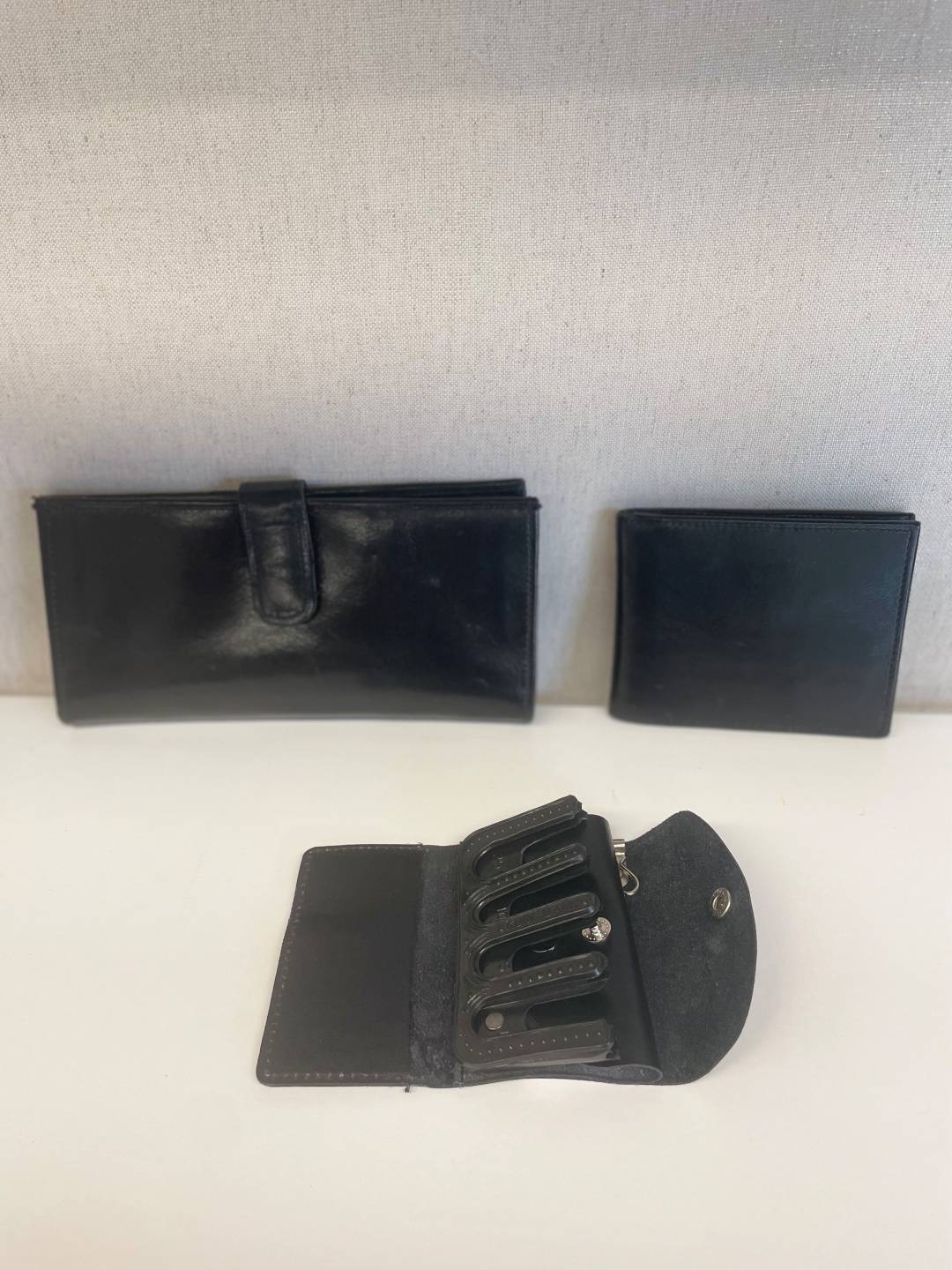 Money Organizers, rectangular leather wallet with pockets on each side and a central clasp for closing, square leather billfold with pockets and slots, square leather coin and key holder, one section has plastic slots for designated coins, the other section has hooks for keys, folds together and snaps close
