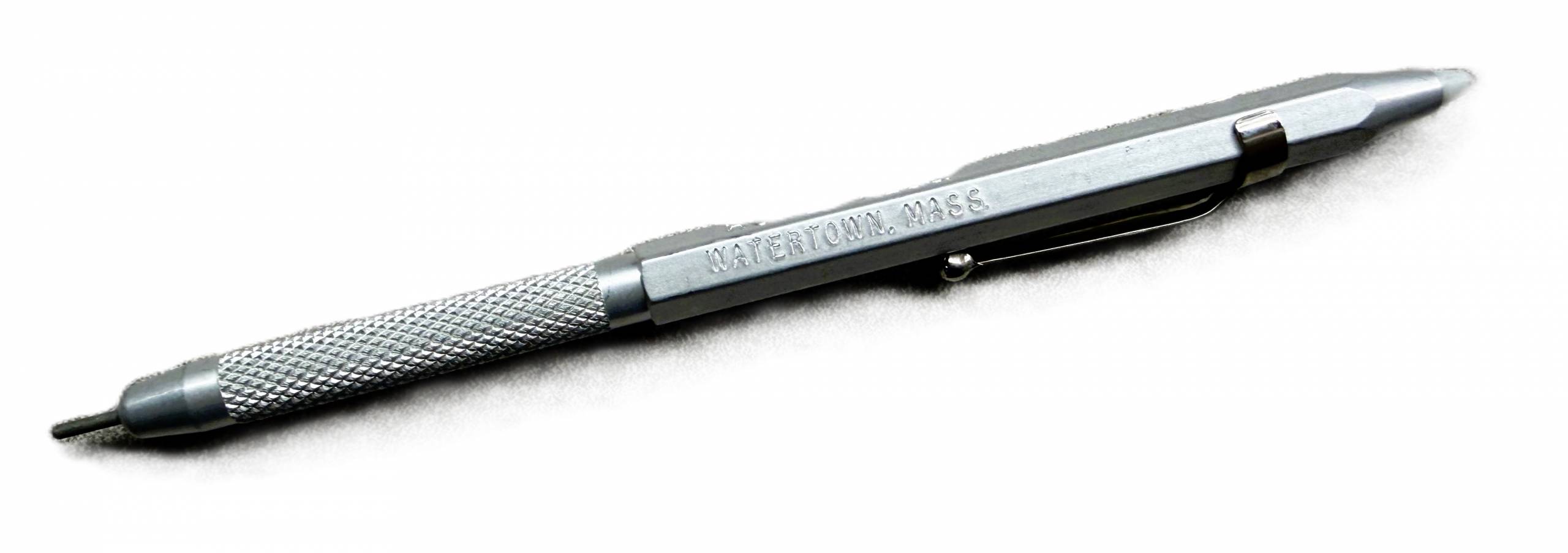 Metal braille stylus in the shape of a pen or pencil with a plastic pointed end and a clip.
