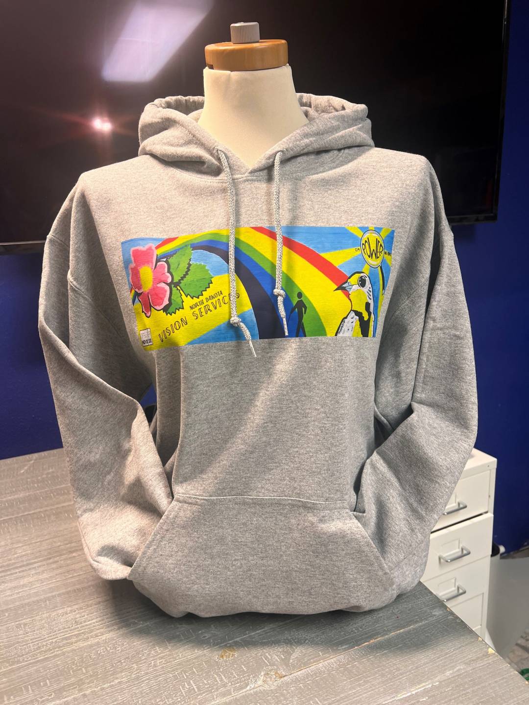 Gray sweatshirt with screenprint of mural, hooded with strings and a front pocket
