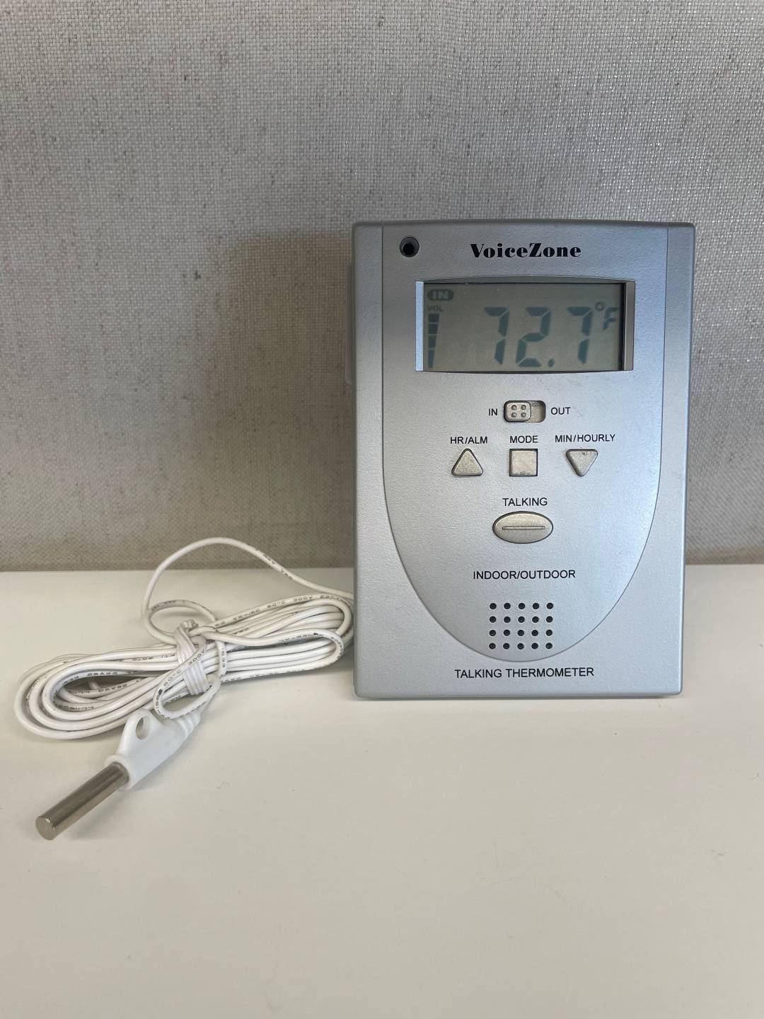 Talking In/Out Thermometer, rectangular monitor with large digital display, toggle switch for inside and outside, four buttons, and a long wire with a sensor on the end to lead outside