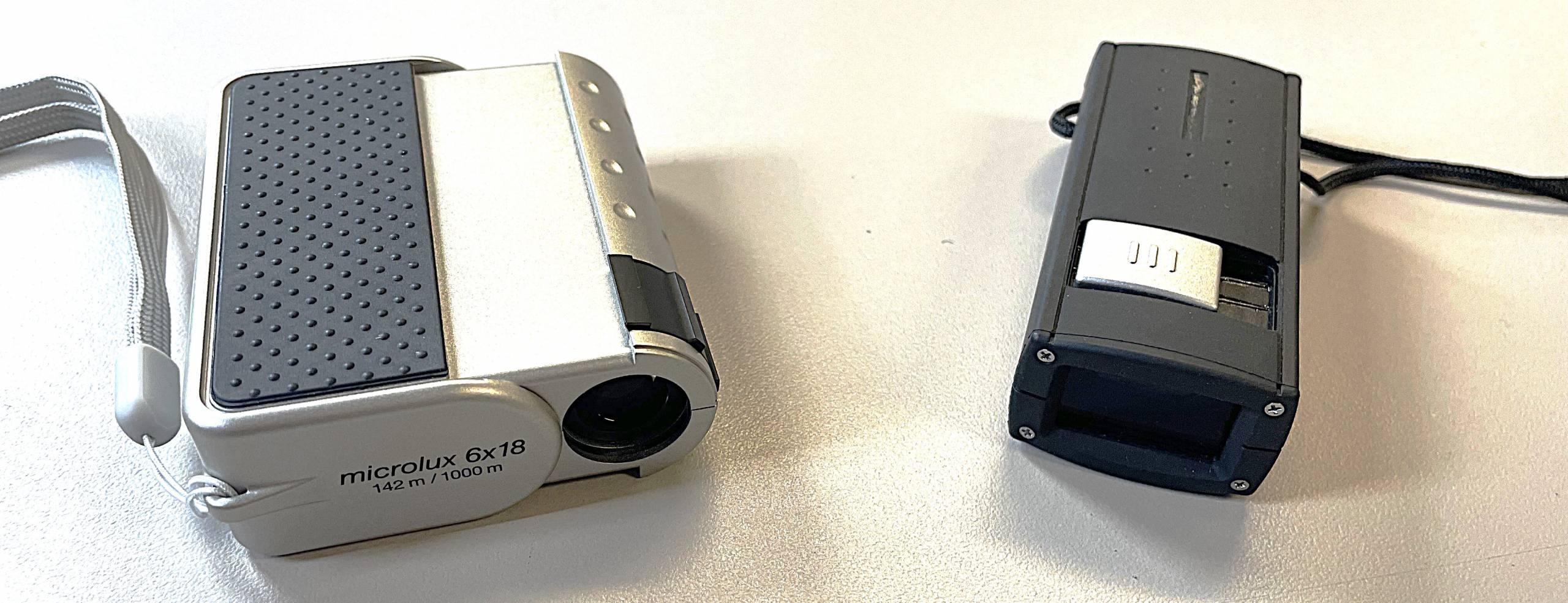 lens that slides out of a silver case with a toggle button on the top, rectangular black lens with a toggle button on the top